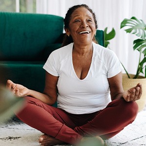 Senior woman smiling while meditating at home