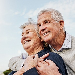 Senior couple smiling while hugging outside