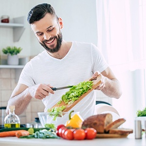 Man smiling while preparing salad in kitchen