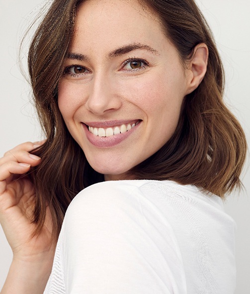 Woman with wavy brown hair glancing over shoulder smiling