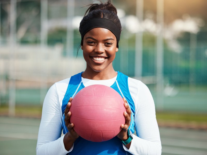Athletic patient with dental implants holding a ball